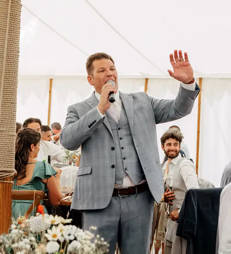 The Wedding Host speaking into a microphone at a marquee wedding reception.