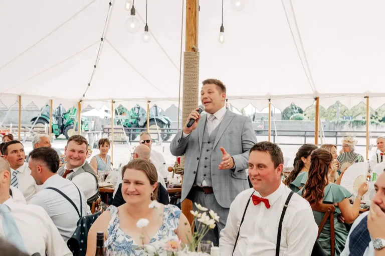 Wedding host entertaining guests during a marquee wedding breakfast.