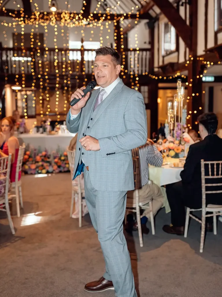 Wedding host speaking into a microphone during a rustic wedding reception.